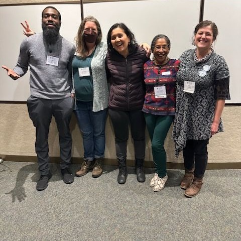 Five people are standing together in front of a whiteboard in a classroom. From left to right, Willie King III, Amy Clarice, Dr. Nigora Erkeava, Paula Sizemore, and Lisa Voelker