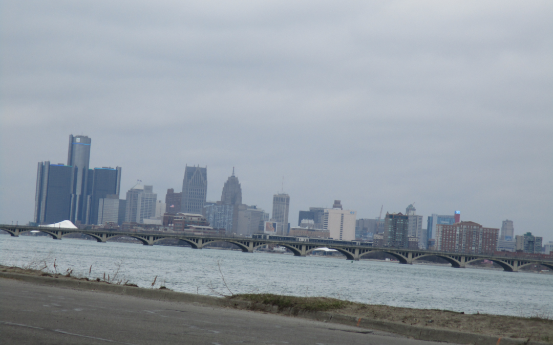 The Detroit skyline with a bridge and the Huron River in front of it, view from the highway