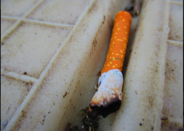 Close-up of a half burned cigarette laying in a groove on a white piece of plastic