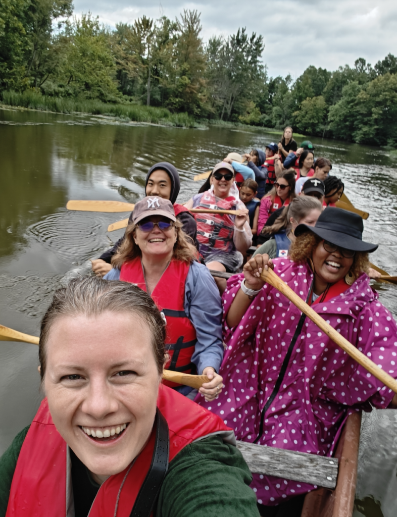 Adult learners take a canoe ride and return from their trip. They have paddles and are smiling.