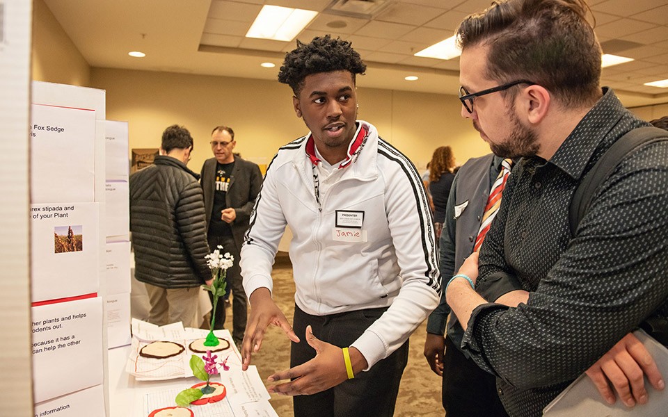 Student at the Community Forum describes his poster to an attendee at the SEMIS Coalition Community Forum